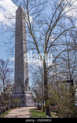Jamestowne, VA, USA - 1. April 2013: Historische Stätte. Pfad zum Tencentennial-Denkmal, umgeben von blühenden Bäumen unter blauer Wolkenlandschaft. Stockfoto