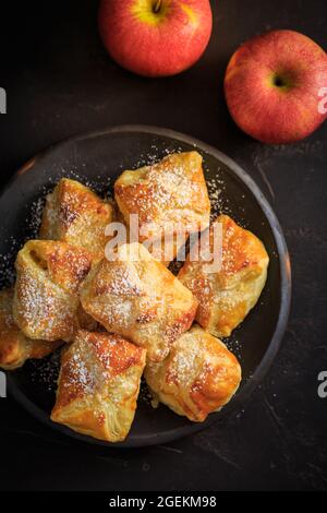 Hausgemachte kleine Apfel-Turnover in Schale auf schwarzem Hintergrund Stockfoto