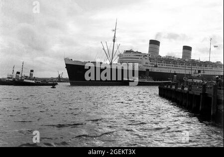 AJAXNETPHOTO. 60ER JAHRE. SOUTHAMPTON, ENGLAND. - HINWÄRTS GEBUNDEN - CUNARD TRANSATLANTIC LINER RMS QUEEN ELIZABETH MIT SCHLEPPERN IN UNTERSTÜTZUNG, FÄHRT AUF EINER IHRER REGULÄREN LINIENFAHRTEN NACH NEW YORK.FOTO:©SUSANNAH RITCHIE COLLECTION/AJAX REF:SR1960S 42 Stockfoto