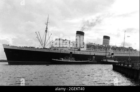 AJAXNETPHOTO. 60ER JAHRE. SOUTHAMPTON, ENGLAND. - HINWÄRTS GEBUNDEN - CUNARD TRANSATLANTIC LINER RMS QUEEN ELIZABETH MIT SCHLEPPERN IN UNTERSTÜTZUNG, FÄHRT AUF EINER IHRER REGULÄREN LINIENFAHRTEN NACH NEW YORK.FOTO:©SUSANNAH RITCHIE COLLECTION/AJAX REF:SR1960S 43 Stockfoto