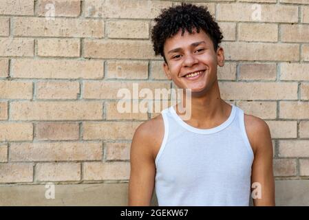 Afro lateinischer Teenager, der an einer Wand lächelt Stockfoto