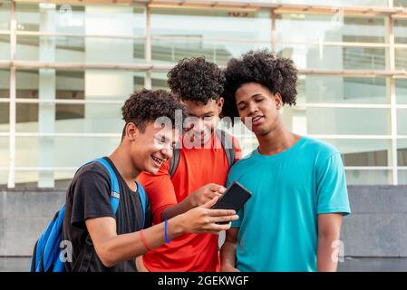 Multiethnische Freunde, die ihr Mobiltelefon auf der Straße nutzen Stockfoto