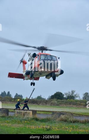 Die US-Küstenwache unterstützt das Navigationsteam Astoria-Besatzungsmitglieder und eine MH-60 Jayhawk-Hubschraubercrew vom Sektor Columbia River bereiten sich darauf vor, Betoncontainer in Astoria, Oregon, am Mittwoch, den 18. August 2021, anzuheben. Beide Mannschaften führten die Betonausbildung durch, um sich auf ein anstehendes Wiederaufbauprojekt vorzubereiten, in dem sie eine Basis für neue Navigationshilfen ausschütten werden. (USA Foto der Küstenwache vom Kleinoffizier der 3. Klasse Diolanda Caballero) Stockfoto