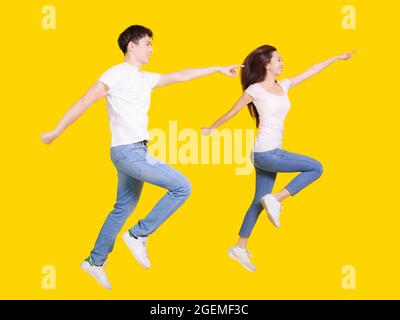 Junges Paar springt und zeigt die Finger auf den Kopierraum .isoliert auf gelbem Hintergrund. Stockfoto