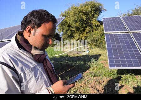 Der indische Landwirt hat auf der Rückseite einen Wasserstrahl installiert, der das Solarpanel über mobile Geräte startet. Stockfoto