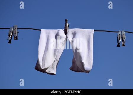 Weiße Socken hingen am Draht, blauer Himmel und Palmen im Hintergrund Stockfoto