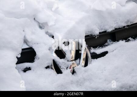 Nahaufnahme EINES schneebedeckten VW-Logos auf EINEM Auto Stockfoto