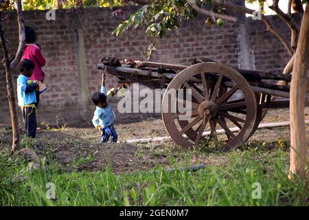 10-01-2020, MP, Indien, ländliche Kinder spielen auf indischen Farmen in der Nähe des alten Rebenwagens. Stockfoto