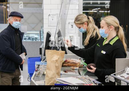 Christchurch, Neuseeland. August 2021. Mitarbeiter von Fresh Choice Supermärkten, die Gesichtsmasken tragen, um die Ausbreitung des Coronavirus zu verhindern, dienen einem Kunden während der Sperre.beim Ausbruch der Delta-Variante in Neuseeland wurden bisher 28 Fälle in Auckland und drei in Wellington bestätigt. Premierminister Jacinda Ardern hat gestern Gebiete außerhalb von Auckland und Coromandel bis Dienstag um 11.59 Uhr weiter gesperrt. Der stellvertretende Premierminister Grant Robertson sagte heute Morgen: „die Dinge werden schlimmer werden, bevor sie besser werden“ und „es wird noch mehr Fälle geben“. Er sagte h Stockfoto