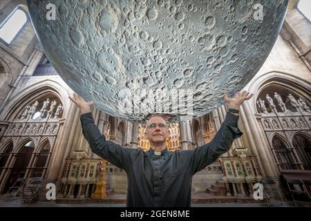 Der Resident Vicar, James Heard, steht mit der Installation des Museum of the Moon des Künstlers Luke Jerram in der St. John the Baptist Kirche im Westen Londons, Großbritannien. Stockfoto