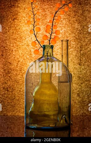 Stillleben mit Glaswaren und einem Zweig mit orangefarbenen Kugeln Stockfoto