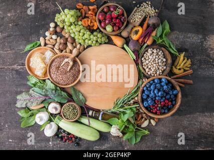 Vegetarische Zutaten zum Kochen. Flaches Gemüse, Obst, Bohnen, Getreide, Küchenutensilien, Getrocknete Blumen, Olivenöl auf einem hölzernen Hintergrund, oben vi Stockfoto