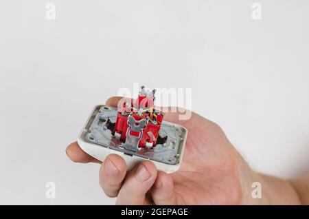 Mann, der eine Computersteckdose vor einem weißen Hintergrund hält. Internet-Buchse für Twisted-Pair-Kabel. Reparaturen, Austausch der Kommunikation. Stockfoto