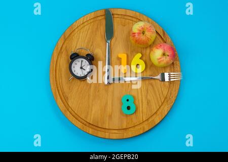 Intermittierendes Fastenkonzept 16:8. Intermittierendes Fasten wird häufig zum Abnehmen oder zur Kontrolle von Diabetes eingesetzt. Blauer Hintergrund Stockfoto