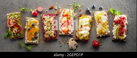 Draufsicht auf Knäckebrot-Toasts mit verschiedenen frischen Früchten und Gemüse in einer Reihe angeordnet Stockfoto