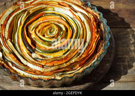 Gemüsekuchen mexikanische Sonne. Runde, offene Torte aus Zucchini, Auberginen und Karotten. Nahaufnahme von oben. Gesunde pflanzliche Lebensmittel. Vegetarismus. Spirale Stockfoto