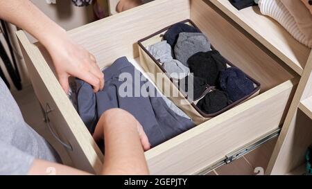 Frau wählt Socken in der Schublade des großen Schranks im Zimmer Stockfoto