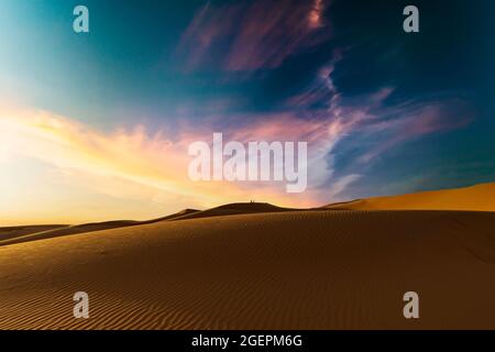 (Selektiver Fokus) atemberaubender Sonnenuntergang über einigen Sanddünen der Merzouga-Wüste in Marokko. Merzouga ist ein kleines Dorf im Südosten Marokkos. Stockfoto