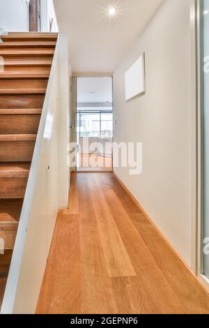 Vertikale Aufnahme eines Eingangs mit einer Holztreppe in einem modernen Wohnhaus im ersten Stock Stockfoto
