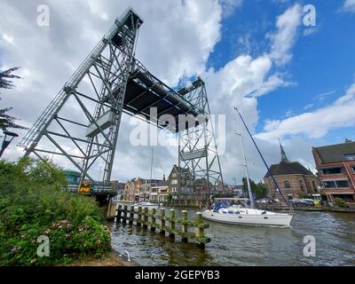 Segelboot mit festem langen Mast an der Stahlhubbrücke über die Gouwe in Boskoop in Südholland in den Niederlanden vorbei Stockfoto