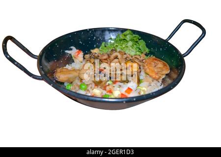 Reis mit Gemüse und gebratene Garnelen in einer gusseisernen Pfanne isolieren sich auf einer weißen Nahaufnahme. Stockfoto