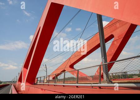 Der Regionalpendler SNG fährt über die rote Hanzeboog-Stahlbrücke über den Fluss IJssel in der Nähe von Zwolle in den Niederlanden Stockfoto