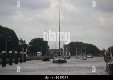 Segelboot mit festem langen Mast auf dem Weg zur Stahl-Hubbrücke über die Gouwe in Boskoop in Südholland in den Niederlanden Stockfoto