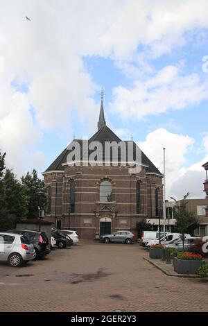 Katholische Kirche namens Dorpskerk in der Altstadt von Boskoop mit Spiegelung der Brücke in den Fenstern Stockfoto