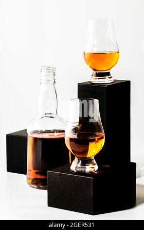 Scotch Whiskey in speziellen Gläsern und Flaschen, schwarze Podien auf weißem Hintergrund Stockfoto