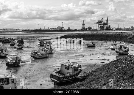 Ein Blick von Paddys Hole, Redcar, England, Großbritannien, zeigt die festgestemmten Boote und den industriellen Hintergrund von Teesport. In Schwarzweiß Stockfoto