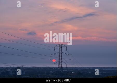Wunderschöne Aussicht am frühen Morgen auf Stromleitungen mit Stromübertragungsmast und epischen violetten Sonnenaufgang über der Irischen See von Ticknock, Co. Dublin aus gesehen Stockfoto