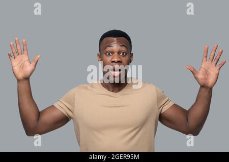 Dunkelhäutiger junger Mann, der überrascht und schockiert aussagt Stockfoto