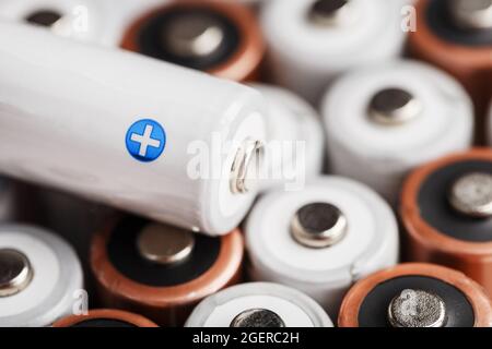 AA-Akkus mit einer weißen Batterie mit positiver Polarität. Selektiver Fokus Stockfoto