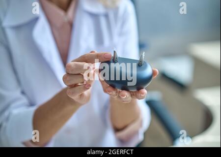 Weibliche Hände, die Hörgeräte im Ständer halten Stockfoto