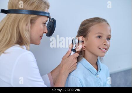 Erfahrener Arzt, der das Ohrhörerrohr in den Gehörgang des Patienten einführt Stockfoto