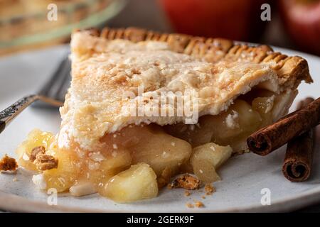 Nahaufnahme einer Scheibe Apfelkuchen und Zimtstangen auf einem Teller Stockfoto