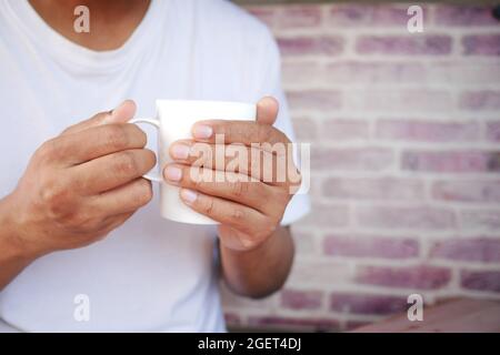 Nahaufnahme von Mann Hand hält Tasse isoliert auf schwarz. Stockfoto