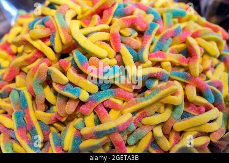 Süße Gummiknüppel mehrfarbige Stäbchen in Form von Würmern auf einem Kirmes-Stand im Stapel Stockfoto