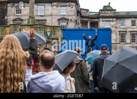 Royal Mile, Edinburgh, Schottland, Großbritannien, 21. August 2021. UK Wetter: Regen am Edinburgh Festival Fringe. Das trostlos nasse Wetter schreckt die Fringe-Massen oder die Straßenkünstler auf einem zurückgeschreckt Festival in diesem Sommer nicht ab. Ein Mann mit einem Kilt, der auf einer Leiter balanciert und mit Macheten jongliert Stockfoto