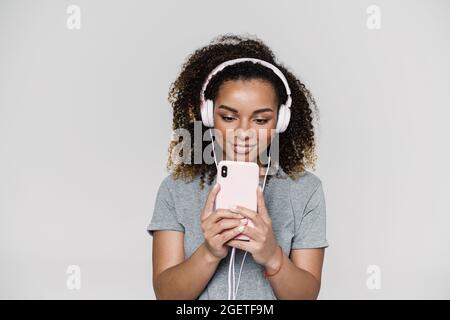 Eine schwarz lächelnde Frau im Kopfhörer, die ein Foto macht, während sie im Lichtstudio steht Stockfoto