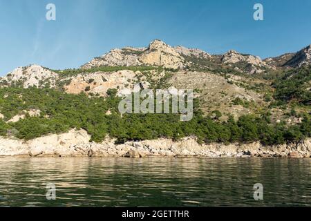 Meer Berge Wald Sommer grüne Landschaft. Wunderschöne Pinien vor dem Hintergrund der grauen Felsen des blauen Himmels. Ein abgeschiedener Ort zum Reisen. Co Stockfoto