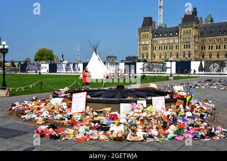 Ottawa, Kanada – 21. August 2021: Tipi wurde von Mitgliedern der Bewegung Blinding Light Walk - Tiger Lily, die von Sudbury aus GING, auf dem Parliament Hill errichtet, um weitere Versöhnungsmaßnahmen und eine weitere Änderung des Indischen Gesetzes von 1876 durch die kanadische Regierung zu bewirken. Die vielen Spielzeuge, die von Menschen zu Ehren der vielen Wohnschüler hinterlassen wurden, sind noch vorhanden Stockfoto