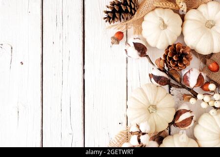 Herbstrand mit weißen Kürbissen und braunen Herbstdekor. Overhead-Ansicht auf weißem Holzhintergrund mit Kopierraum. Stockfoto