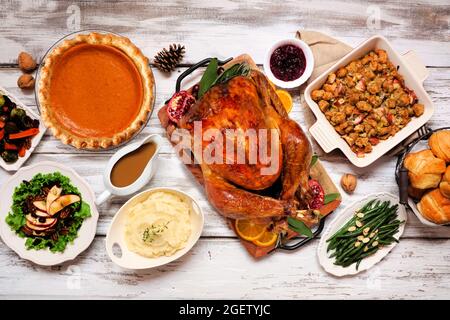 Klassisches Thanksgiving putenessen. Deckenansicht Tischszene auf einem rustikalen weißen Holzhintergrund. Pute, Kartoffelpüree, Füllung, Kürbiskuchen und Si Stockfoto