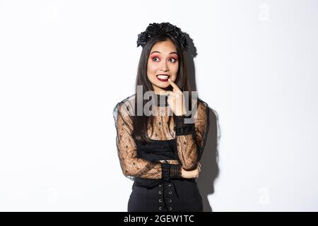 Bild von fasziniert junge nette Frau in Hexenkleid, feiert halloween, denken über etwas Interessantes, Blick links oben, stehend Stockfoto