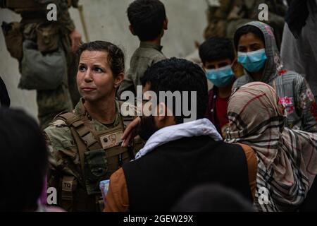 Kabul, Afghanistan. August 2021. Ein US-Luftwaffe mit der Gemeinsamen Task Force „Crisis Response“ spricht mit Familien, die während einer Evakuierung am internationalen Flughafen Hamid Karzai in Kabul, Afghanistan, am 20. August 2021 auf die Verarbeitung warten. US-Dienstmitglieder unterstützen das Außenministerium bei einer nicht-kämpferischen Evakuierungsoperation (NEO) in Afghanistan. Foto von CPL. Davis Harris/USMC/UPI Credit: UPI/Alamy Live News Stockfoto