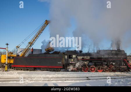 SORTAVALA, RUSSLAND - 10. MÄRZ 2021: Verladung von Kohle in einen Dampflokomotivwagen am Bahnhof Sortavala Stockfoto