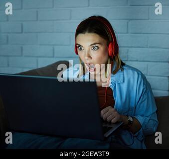 Laptop Computer Kopfhörer Film erschreckt überrascht Nacht dunkel aussehende Mädchen glühenden Bildschirm spät Stockfoto