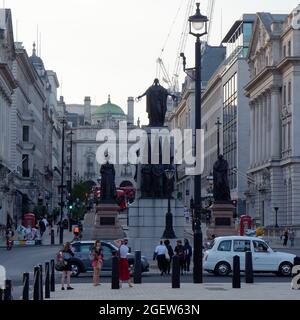 Waterloo Place. Frauen, die vom Krimdenkmal der Garde fotografiert wurden. Piccadilly Circus im Hintergrund. Stockfoto