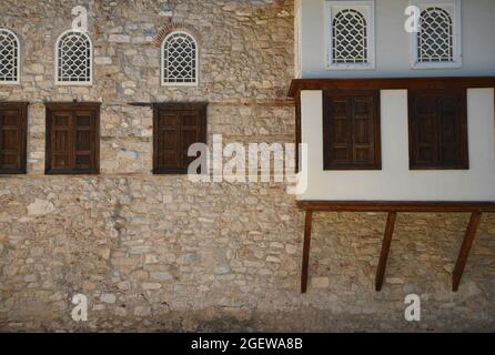 Traditionelle Villa im Balkan-Stil mit einer handgefertigten Steinwand und Fenstern mit Holzfenstern in Anafiotika, Athen, Griechenland. Stockfoto